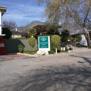 A view of a residential building with prominent signage surrounded by trees and a clear sky.