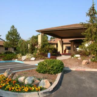 Entrance to a building with landscaped garden and parking lot.