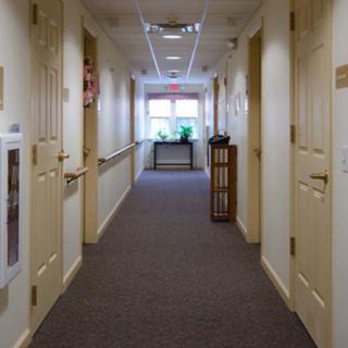 A well-lit hallway with carpeted flooring and doors on either side.