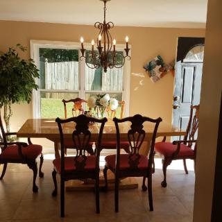 A well-lit dining room with a wooden table, chairs, and a chandelier.