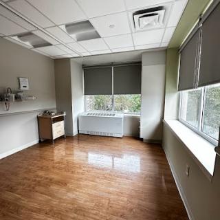 A spacious and minimalistic office room with large windows and simple furnishings.