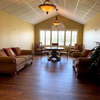 A spacious living room with comfortable sofas, a dining table with chairs, and large windows providing natural light.
