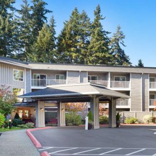 A hotel building with a covered entrance surrounded by tall trees.