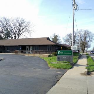 A commercial building situated on a corner lot with a sidewalk and parking area.