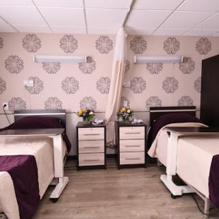 A well-designed hospital room featuring two patient beds, modern furniture, and tasteful floral decorations.
