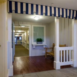 A well-lit hallway with a striped canopy and wooden flooring.