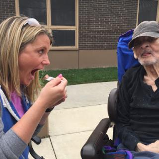 A joyful moment shared between a caregiver and a resident, enjoying ice cream together.