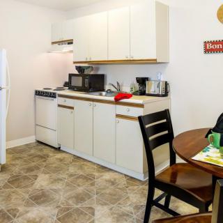 A compact kitchen space in an apartment with basic amenities including an oven, microwave, and a dining area.