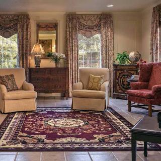 A cozy living room with armchairs, a patterned rug, and elegant drapes.
