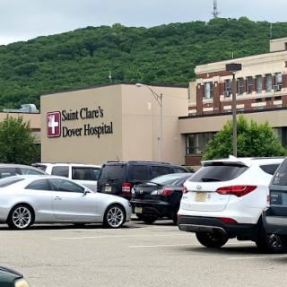 A view of Saint Clare's Dover Hospital with a busy parking lot and surrounding greenery.