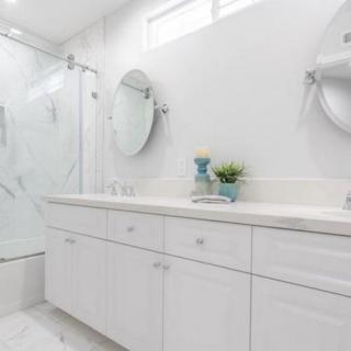 A modern, white bathroom with a shower and neatly organized counter space.