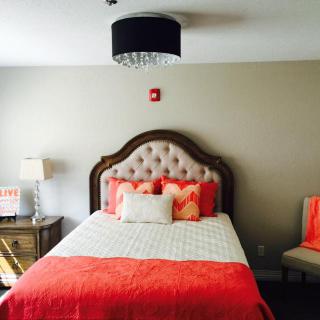 A cozy bedroom with a tufted headboard and orange accents on the bedding and decor.
