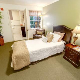 A cozy bedroom featuring a neatly made bed with cushy pillows, elegant nightstands, and warm lighting.