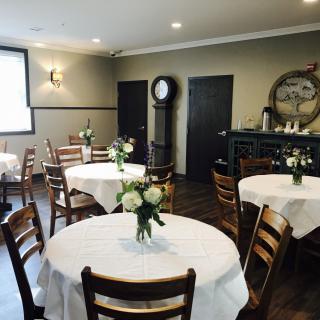 A cozy restaurant interior with round tables and floral centerpieces.