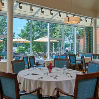 A well-lit restaurant dining area with elegantly set tables and a view of the outdoor patio.