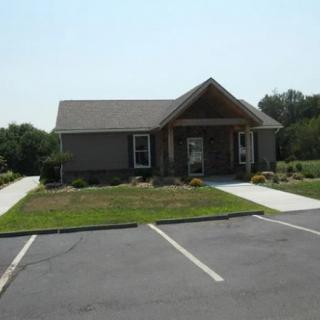 A small suburban house with a parking lot and lawn.