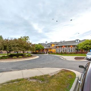 A view of a building with a parking lot and trees during the evening.