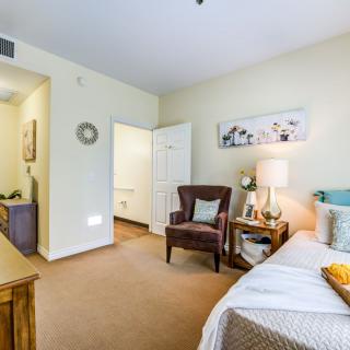 A cozy bedroom with a comfortable chair, bedside table, and soft lighting.