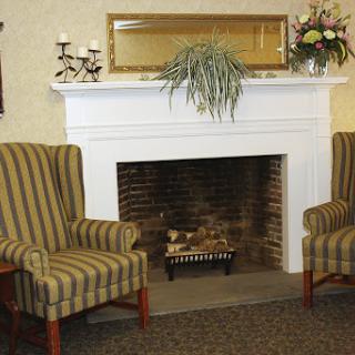 A cozy living room setting featuring a classic fireplace, comfortable striped chairs, and decorative elements.