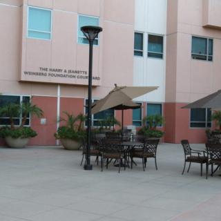 Outdoor seating area with tables and umbrellas near a building.
