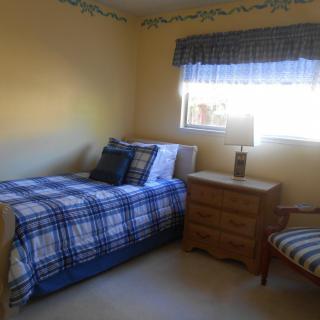 A cozy bedroom with plaid bedding and natural light streaming through the window.