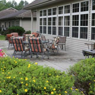 A cozy outdoor patio with a table and chairs surrounded by greenery.