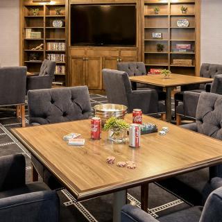 A cozy meeting room with bookshelves, comfortable seating, and a central table surrounded by chairs.