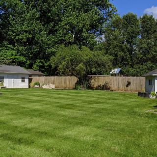 A well-maintained backyard with a lush green lawn, surrounded by a wooden fence and trees.