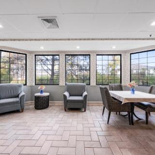 A bright and spacious sunroom featuring comfortable seating and a dining area with large windows offering a view of the outdoors.
