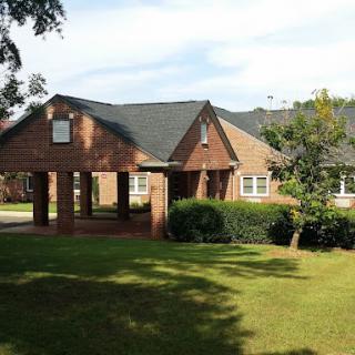 A brick residential building with a well-kept lawn on a sunny day.