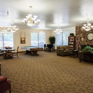 A spacious recreation room featuring a pool table, comfortable seating, and elegant chandeliers.