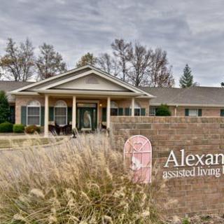 A brick building with an entrance and a sign in front, surrounded by landscaping under an overcast sky.
