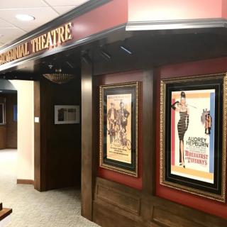 A classic-themed theater interior with framed movie posters adorning the wall.