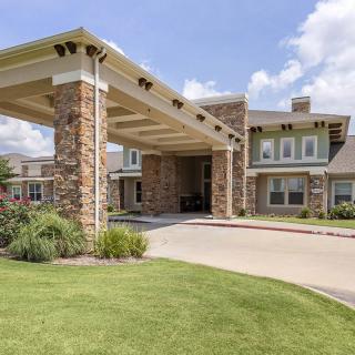 A modern residential building with a stone facade and landscaped entrance.