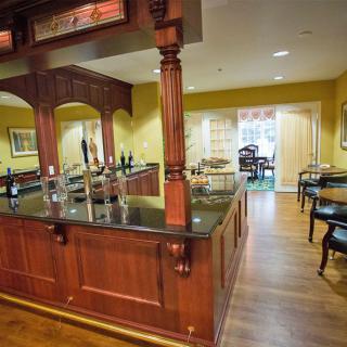 A cozy restaurant interior featuring a wooden bar counter and dining area.