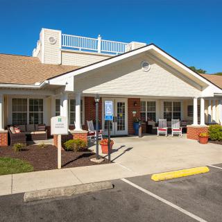 The front entrance of a residential care facility with a small parking area in front.