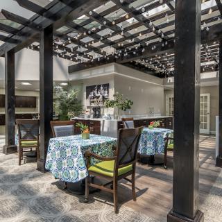 An inviting outdoor seating area with tables and chairs under a pergola.