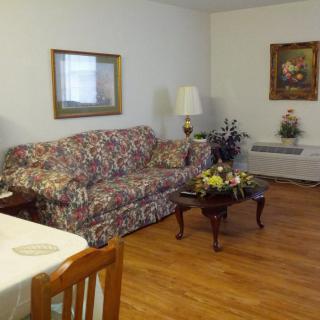 A cozy living room with a floral sofa, coffee table, lamps, and artwork on the walls.