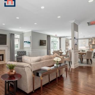 A spacious open-concept living room with modern decor, featuring a cozy sofa and dining area with wood flooring.