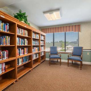 A cozy reading nook in a library with wooden bookshelves and comfortable chairs by the window.