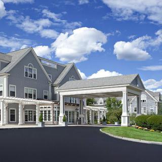 A large residential building with an entrance driveway under a blue sky with clouds.