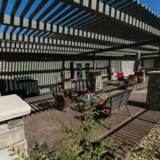 A patio area with a pergola casting shadows over outdoor seating and landscaping.