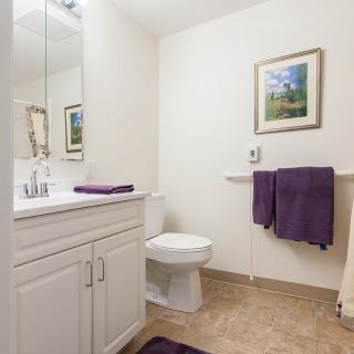 A tidy bathroom with white cabinets and purple towels.