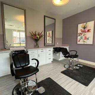 A modern hair salon interior with styling chairs and large mirrors.