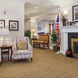 A cozy living room featuring a fireplace, armchair, and an American flag.
