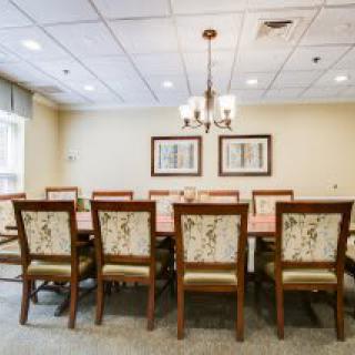 A spacious dining or meeting room with a long table and upholstered chairs.