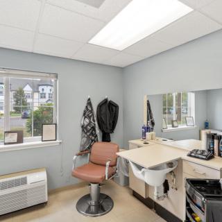 A well-lit hair salon interior with a styling chair, mirror, and sink.