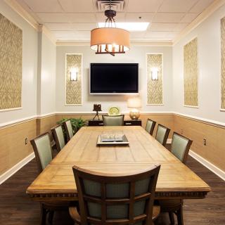 A well-appointed conference room with a large wooden table, cushioned chairs, and a mounted television.