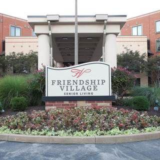 Entrance to Friendship Village with a welcoming garden and sign.