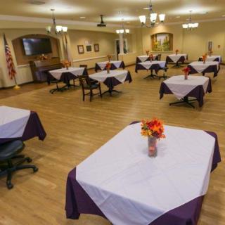 A decorated dining area with tables set with white tablecloths and flower centerpieces.
